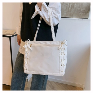Detail of white ita bag showing side ribbon lace-up design and transparent PVC display panel