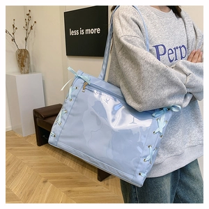 Detail of light blue ita bag showing side ribbon bow tie and transparent PVC front pocket