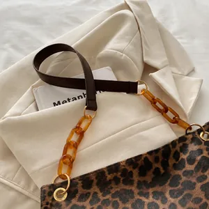 Detail van de luipaardprint tote met amberkleurige ketting en lederen schouderriem