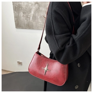 Détail du sac hobo en similicuir rouge avec étoile argentée sur un manteau en laine noir