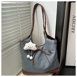 Détail du cabas en denim avec finitions en cuir marron, nœud et charme nuage