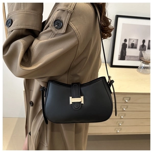 Detail view of smooth black leather shoulder bag with elegant golden metal buckle closure