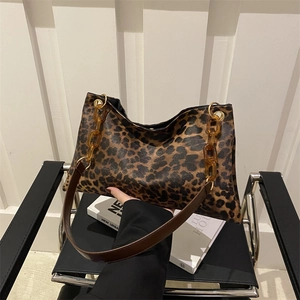 Bolso tote de leopardo con cadenas de acrílico ámbar y correa de cuero en silla de piel