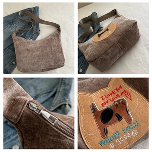 Detailweergave van bruine corduroy schoudertas met kattenborduursel en rits