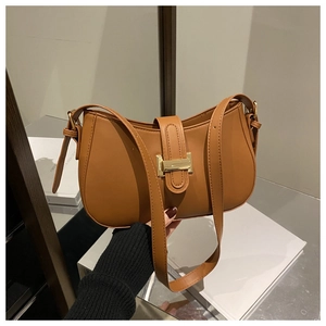 Detail of a brown leather crescent shoulder bag with a gold rectangular metal buckle