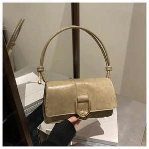 Détail du sac en cuir beige ciré avec fermoir doré en U et poignée à nœud décorative
