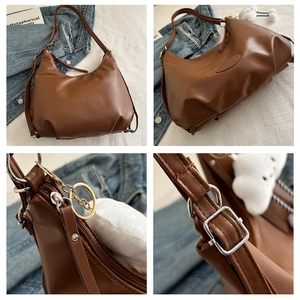 Detail view of brown leather tote showing silver hardware buckles and pleated texture