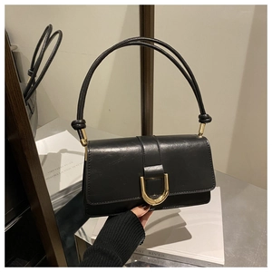 Détail d'un sac à main noir en similicuir brillant avec boucle en U dorée et poignée nouée