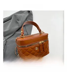 Dettaglio borsa trapuntata caramello con accessorio in metallo floreale e tracolla a catena