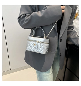 Dettaglio borsa a secchiello trapuntata argento con catena oro e zip a fiore
