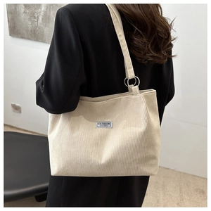 Dettaglio della borsa tote in velluto a coste crema con trama a righe e logo patch