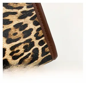 Detailed close-up of leopard print fabric texture and premium brown leather piping edges