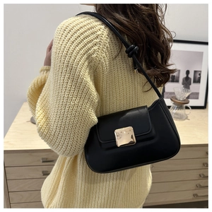 Detailansicht der schwarzen Baguette-Tasche mit großer goldener Schnalle am Modell