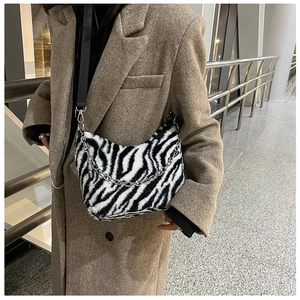 Detail of zebra print plush tote with silver chain handle and black shoulder strap