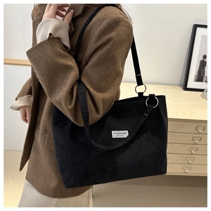 Dettaglio della borsa tote in velluto a coste nero con trama e etichetta alla moda
