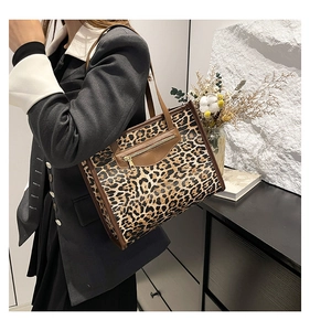 Detail of leopard print tote bag featuring brown leather trim and metal zipper pocket