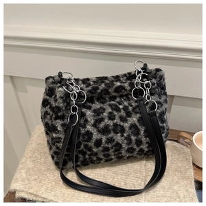 Detail der grauen Leoparden-Plüschtasche mit Metallkette auf gestricktem Hintergrund