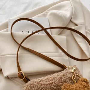 Close-up of brown leather shoulder strap with gold metal buckle on plush bucket bag