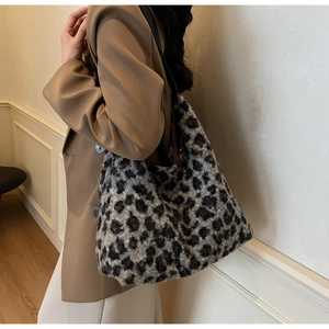 Detailed texture of plush leopard print shoulder bag worn by model in minimalist setting