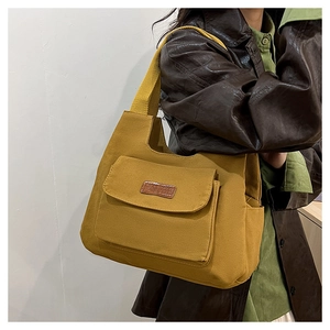 Vista dettagliata della borsa tote in tela gialla con tasca frontale e logo in pelle