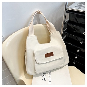 Dettaglio della borsa tote in tela con tasca laterale e toppa in pelle marrone moda