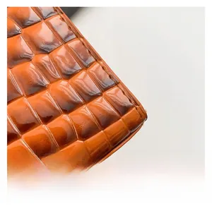 Détail du cuir embossé crocodile marron-orangé avec finition brillante et couture fine