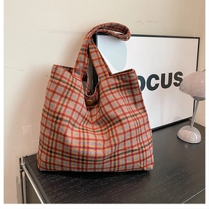 Detailed view of plaid wool tote bag with classic check pattern and brown button closure