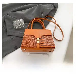 Détail du sac orange avec texture crocodile embossée et fermoir pivotant en métal
