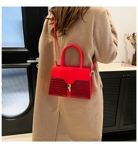 Détail du sac bandoulière en cuir rouge avec motif crocodile et boucle métallique