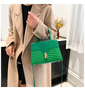 Détail du sac à main vert motif pierre avec fermoir doré porté avec un manteau beige