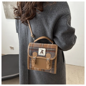 Détail du sac à main vintage en laine à carreaux avec écusson d'ours et boucles