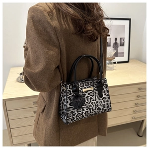 Détail du sac léopard avec pompon en peluche et poignée supérieure noire