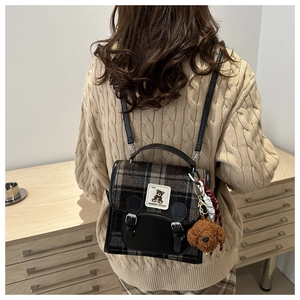 Détail du sac à dos en laine à carreaux avec finitions cuir et charm de chien en peluche