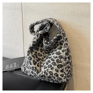 Detailed view of leopard print plush tote bag on a textured surface with accessories