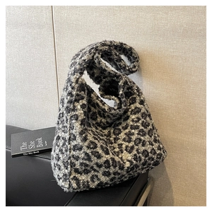 Close-up of leopard print plush tote bag showing soft sherpa texture on leather sofa