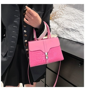 Détail du sac bandoulière rose avec texture crocodile et fermoir rotatif argenté