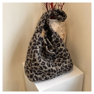 Detail of plush leopard print tote bag on a white display stand with winter decor