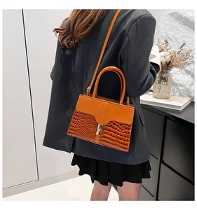 Détail du sac à main avec texture crocodile, rabat orange et fermoir en métal doré