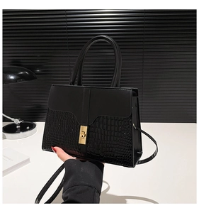 Detail of black satchel with faux crocodile texture and gold square turn-lock closure