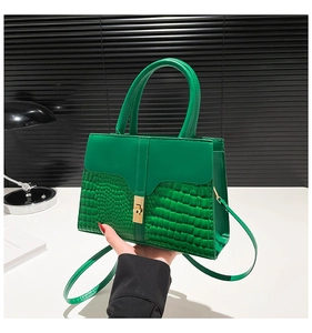 Detail of green crocodile pattern handbag with gold clasp and adjustable strap