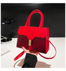 Close-up of red handbag featuring croc-embossed texture and gold square lock detail