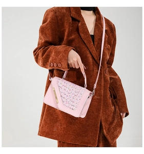 Détail d'un sac bandoulière rose avec rabat en tweed sur une veste de blazer marron