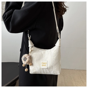 Detail of white textured shoulder bag with MIAO SHE logo and blue tear plush charm