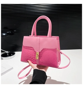 Detail of pink croc-embossed leather handbag with gold twist lock and smooth top handle