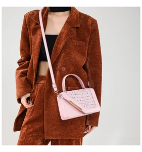 Sac à main rose en cuir avec détails en tweed, porté par un mannequin avec un blazer en velours