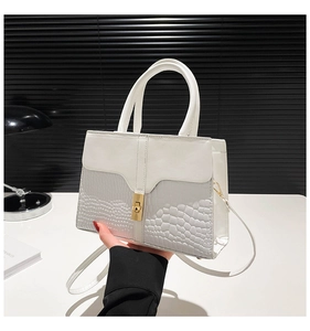 Detail of white handbag featuring crocodile texture mix and gold twist lock closure