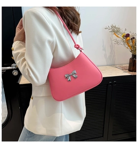Vue détaillée du sac à bandoulière rose avec un nœud argenté porté par un mannequin