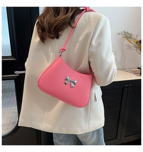 Détail du sac à bandoulière rose avec nœud argenté et bandoulière nouée porté par un mannequin