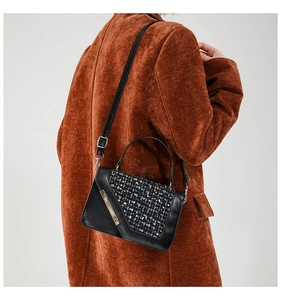 Détail du sac en cuir noir avec rabat en tweed coloré et barre dorée décorative