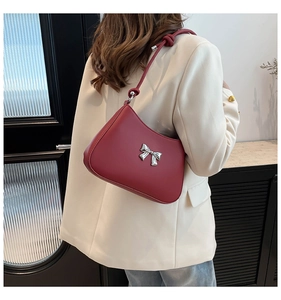 Détail du sac rouge avec boucle nœud argentée et bandoulière nouée porté par le mannequin